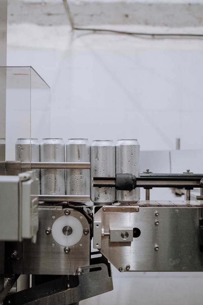 Ürünlerimiz Vertical shot of aluminum cans on a conveyor in a factory setting, showcasing industrial processes.